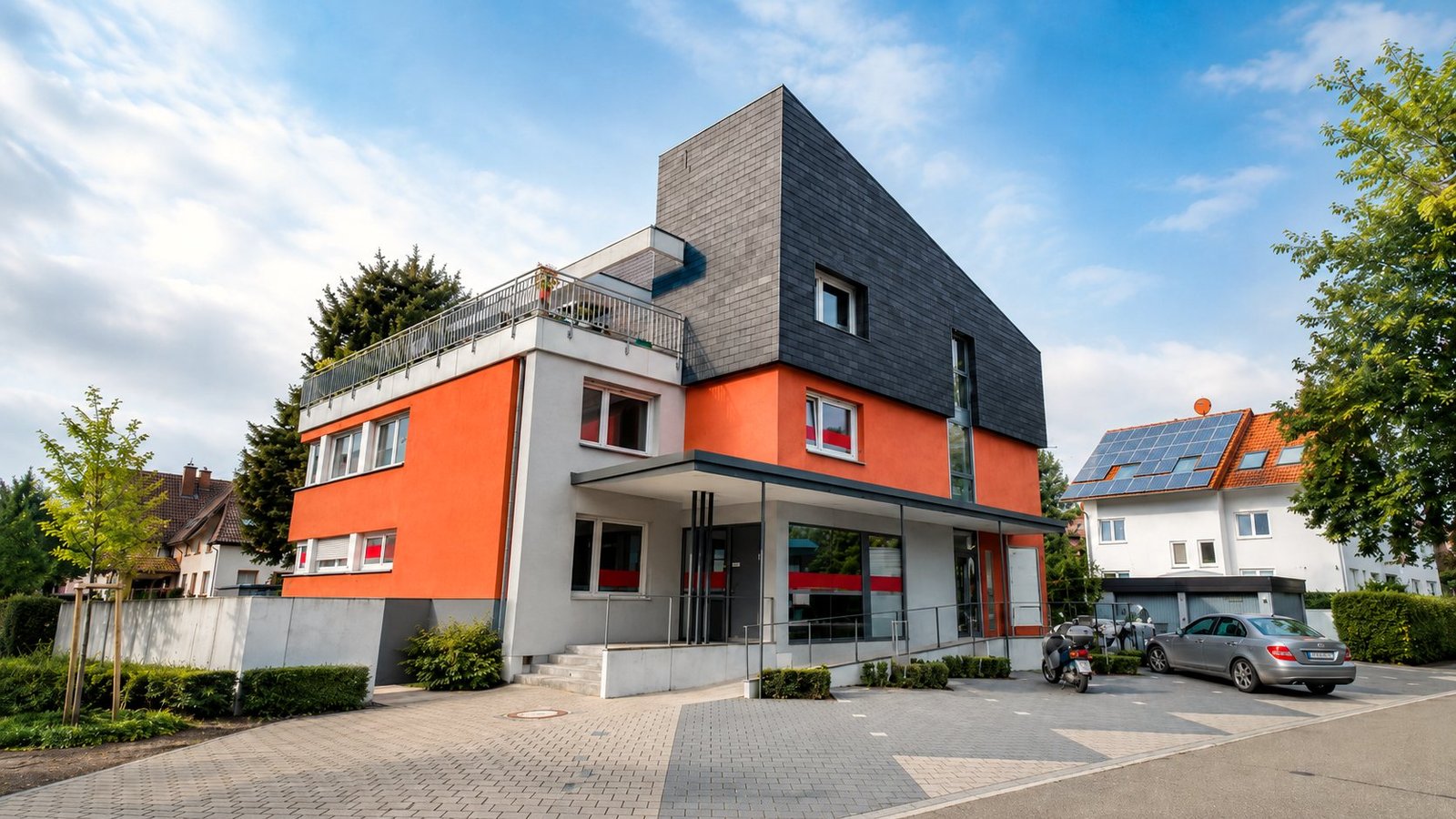 Das Praxisgebäude Am Vogelsang 2 in Achern mit oranger Fassade und überdachtem Eingang