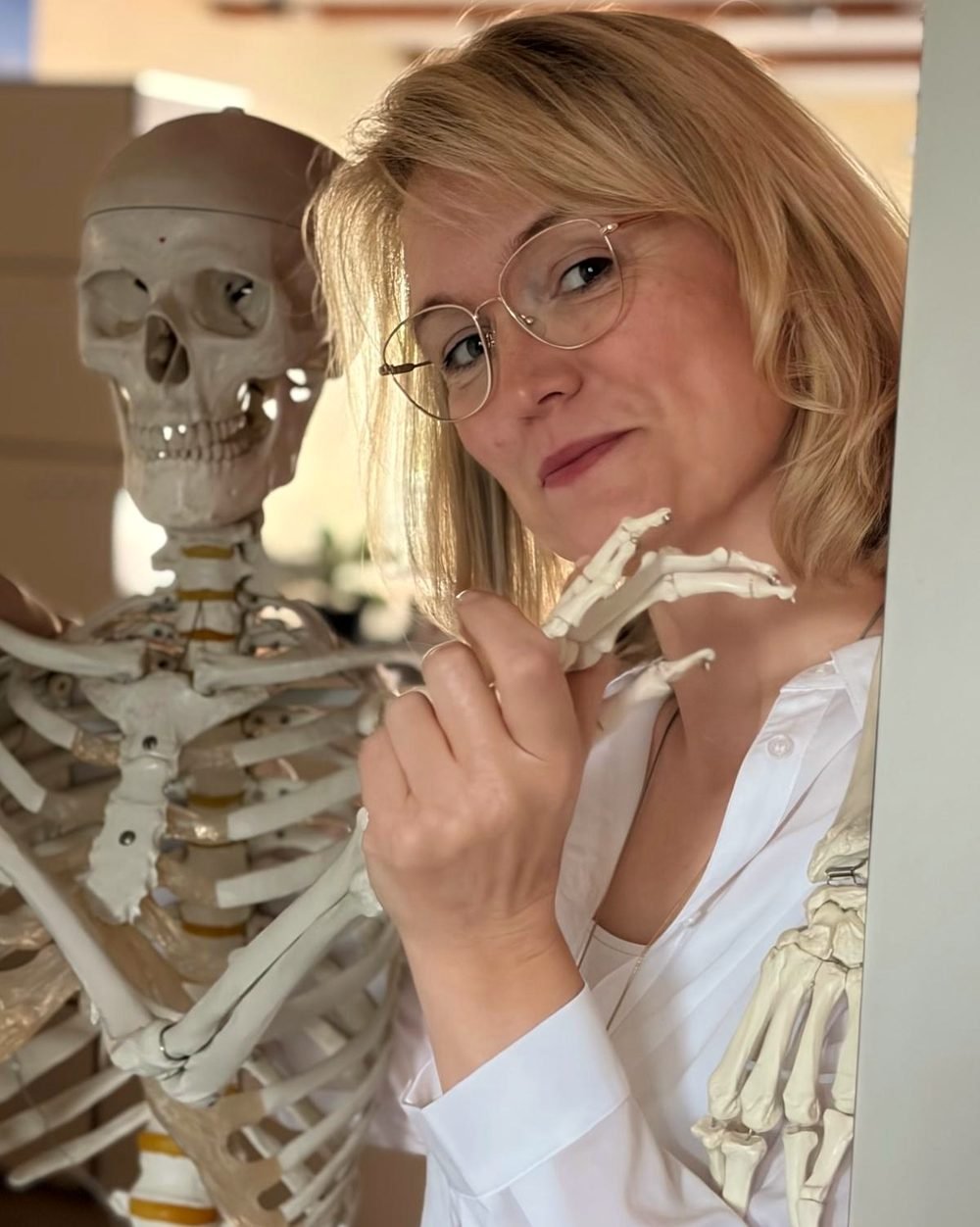 Porträt von Yvonne Voß neben einem anatomischen Skelettmodell